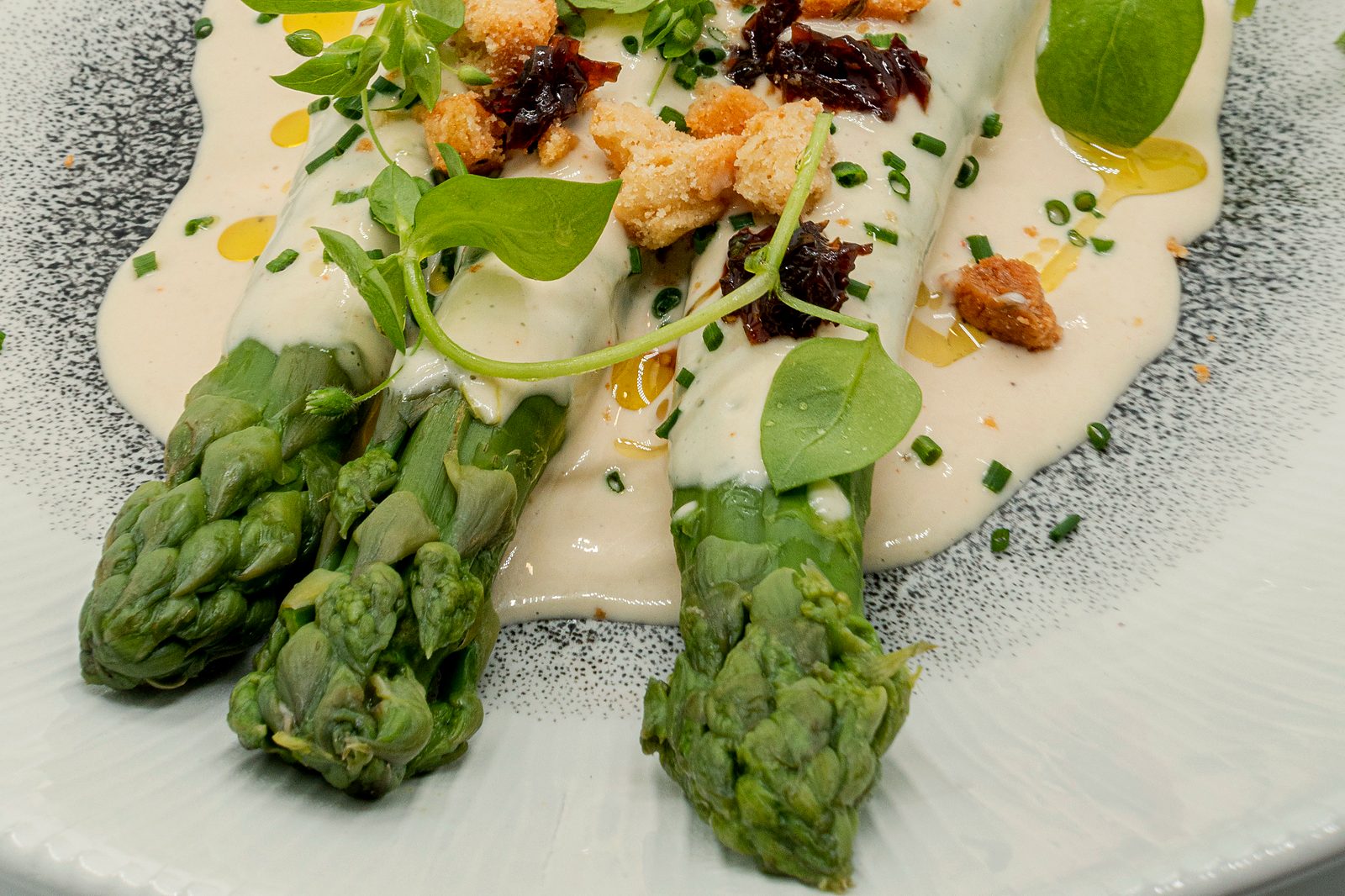 Asperges vertes nappées d’une sauce crémeuse, croûtons dorés, pousses et ciboulette, une entrée de saison au restaurant L’Apibo, rue Tiquetonne à Paris 2e