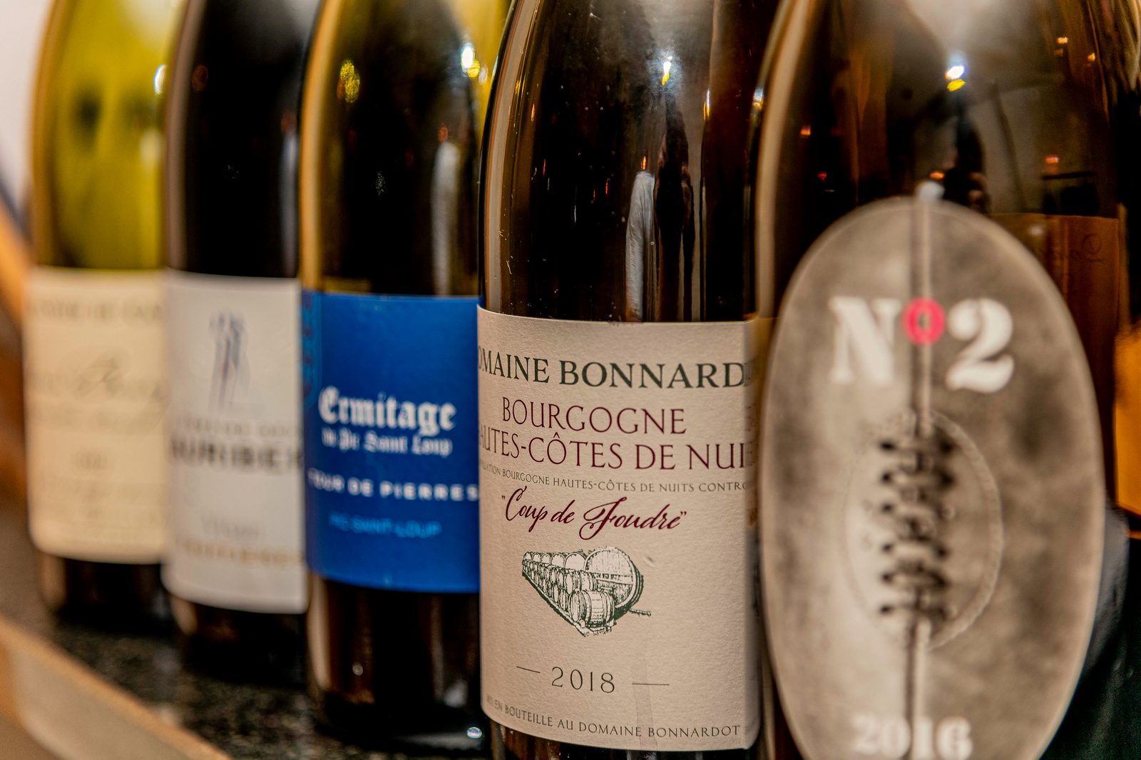 Bouteilles de la cave de L’Apibo alignées sur le comptoir : bourgognes, ermitage et cuvées de domaines français choisis par la maison, à Paris