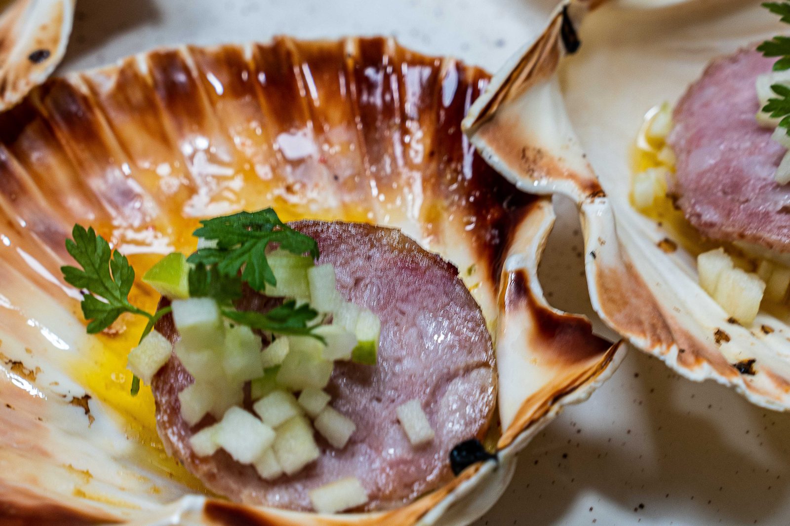 Saucisse de Morteau de L’Apibo servie en coquille Saint-Jacques : tranche fumée, dés de pomme verte et cerfeuil, entrée à Paris 2e